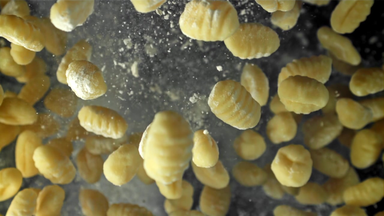 Gnocchi freschi che cadono con farina al rallentatore