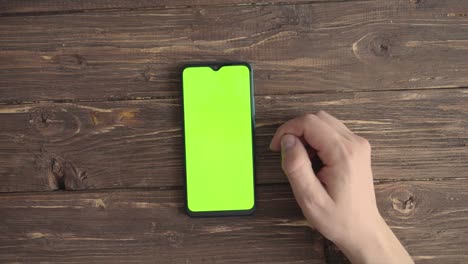 male hands with a smartphone with a chroma key on the table. view from above