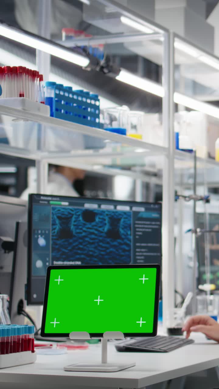 Vertical video Bioinformatics scientist working on green screen tablet in lab