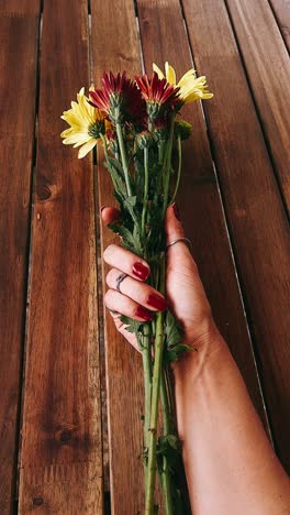 mujer sosteniendo un ramo de flores en una mesa de madera
