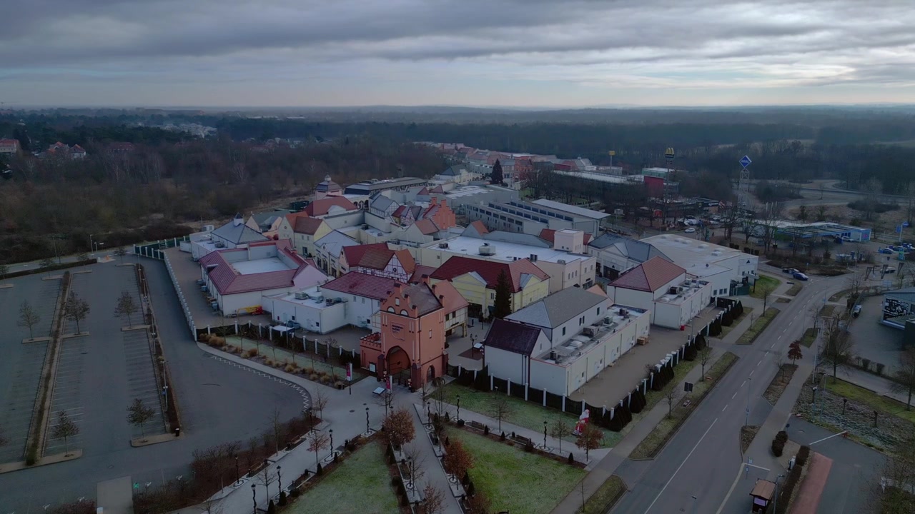 Um grande centro comercial outlet com vários edifícios, lojas de varejo e um estacionamento vazio. Vista aérea majestosa de drone em panorama.