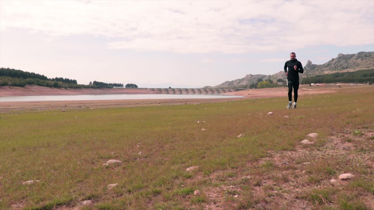 느린 동작으로 호수 옆 초원에서 달리는 사람