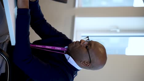 black bald professional man typing on a laptop in a meeting room