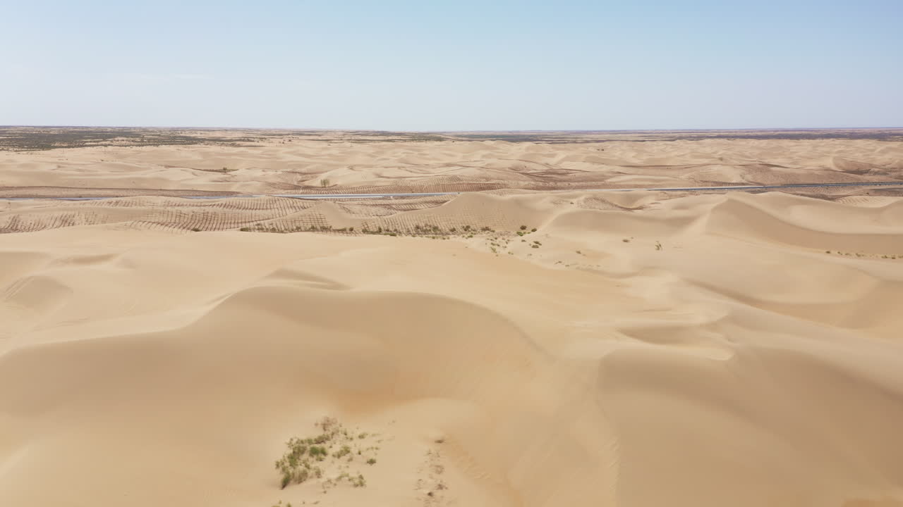 panning drone toma de las dunas de arena que bordean una carretera en el desierto de gobi
