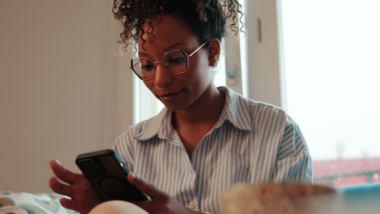 Woman Using Smartphone on Couch by Window