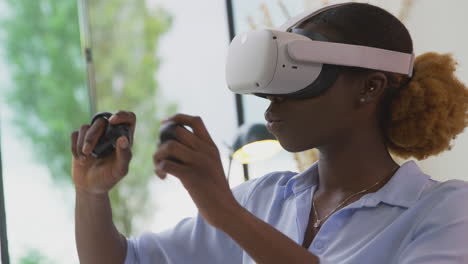 woman working from home office with controllers wearing vr headset interacting with ar technology