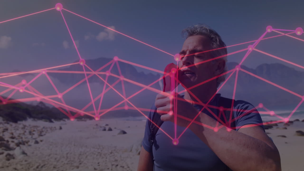 Mature man adjusting mask strap on rocky beach, showing pink network overlay for tech data