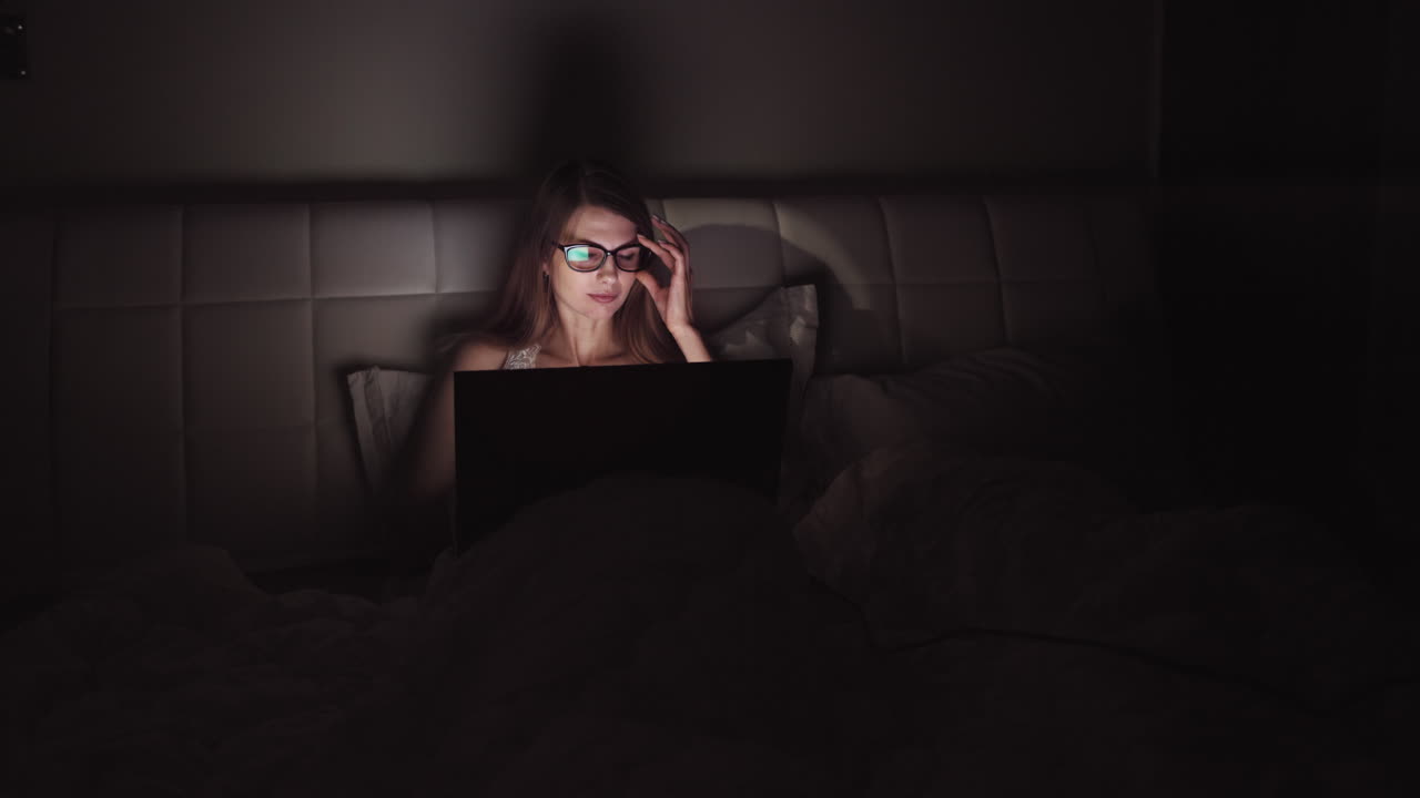 mujer trabajando en la computadora portátil en la cama por la noche