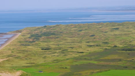 pan from tourist car park to reveal landscape of grass sand dunes with loughor estuary in background in wales uk 4k