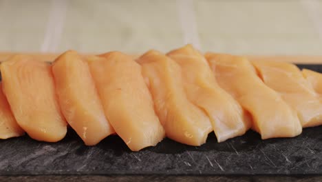 Cutting with knife raw chicken meat on desk close-up. Preparing raw food for cooking. Grilled chicken, duck, turkey kebab with vegetables.