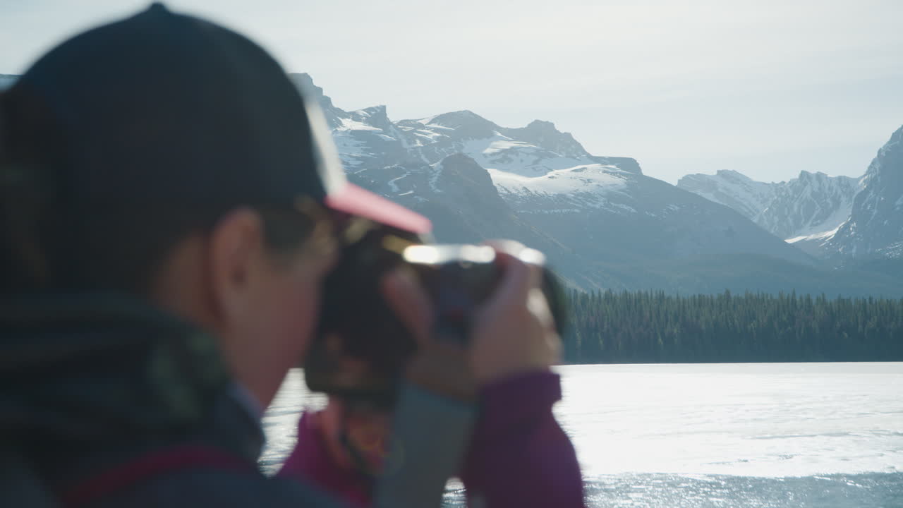Woman Takes Pictures of Ice Covered Maligne Lake, Background in Focus