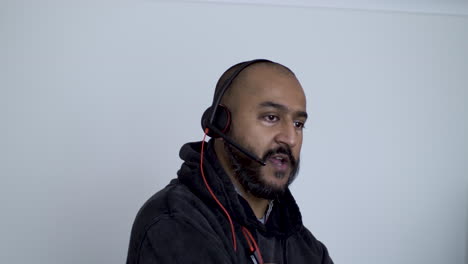 a close up shot of an indian call centre employee taking a call from a returning customer, the man pacing the room and agreeing in conversation as he provides advise and support to the caller
