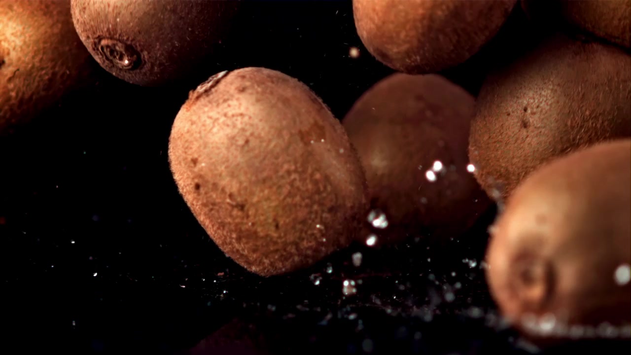 Kiwi freschi che si tuffano nell'acqua su sfondo nero