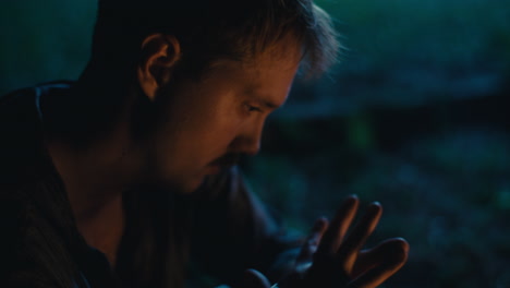 a man's thoughtful moment by the campfire at night