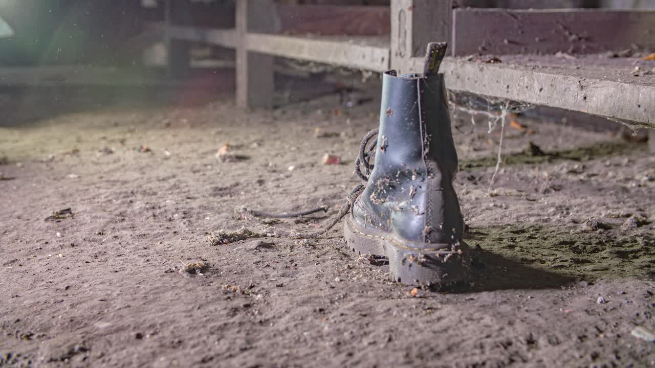 old work boots dropping on the ground. Dirty soil floor, rural place