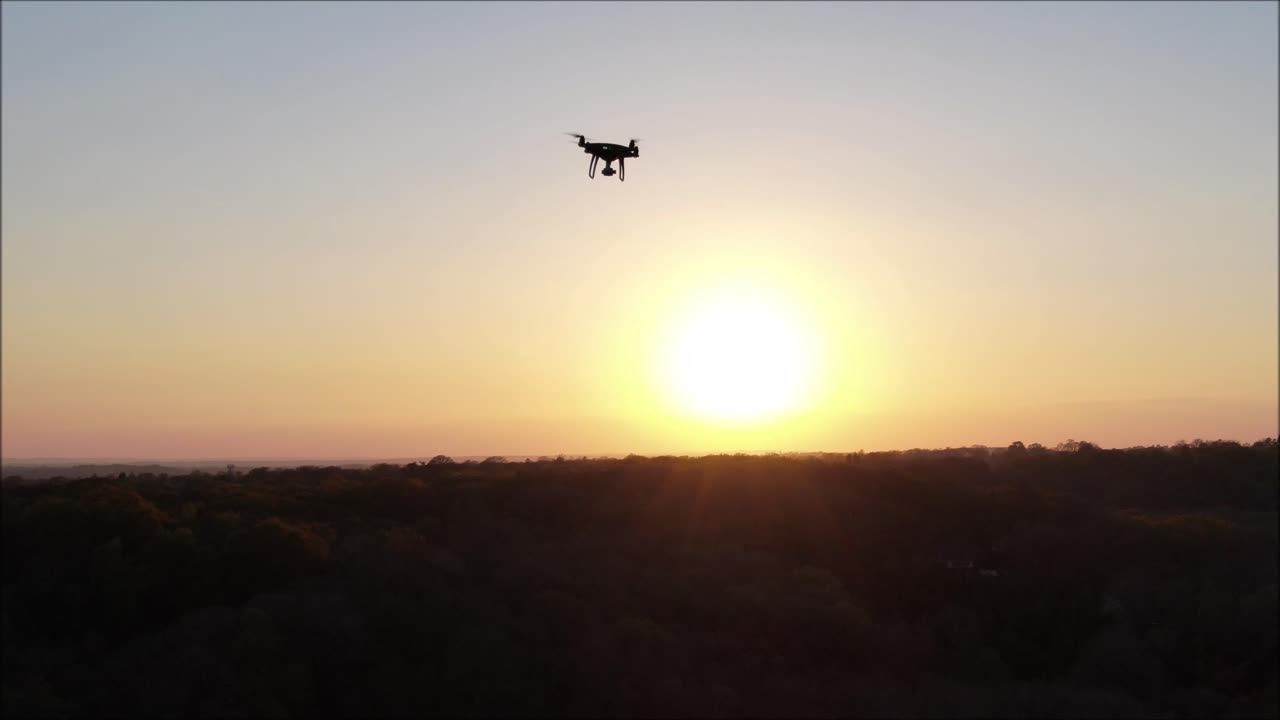 Drone flying in the sunset filmed from another drone.