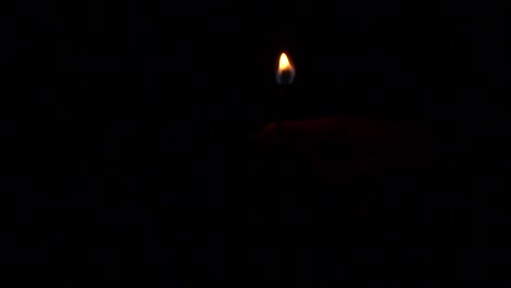 hand holding lighted match in movement