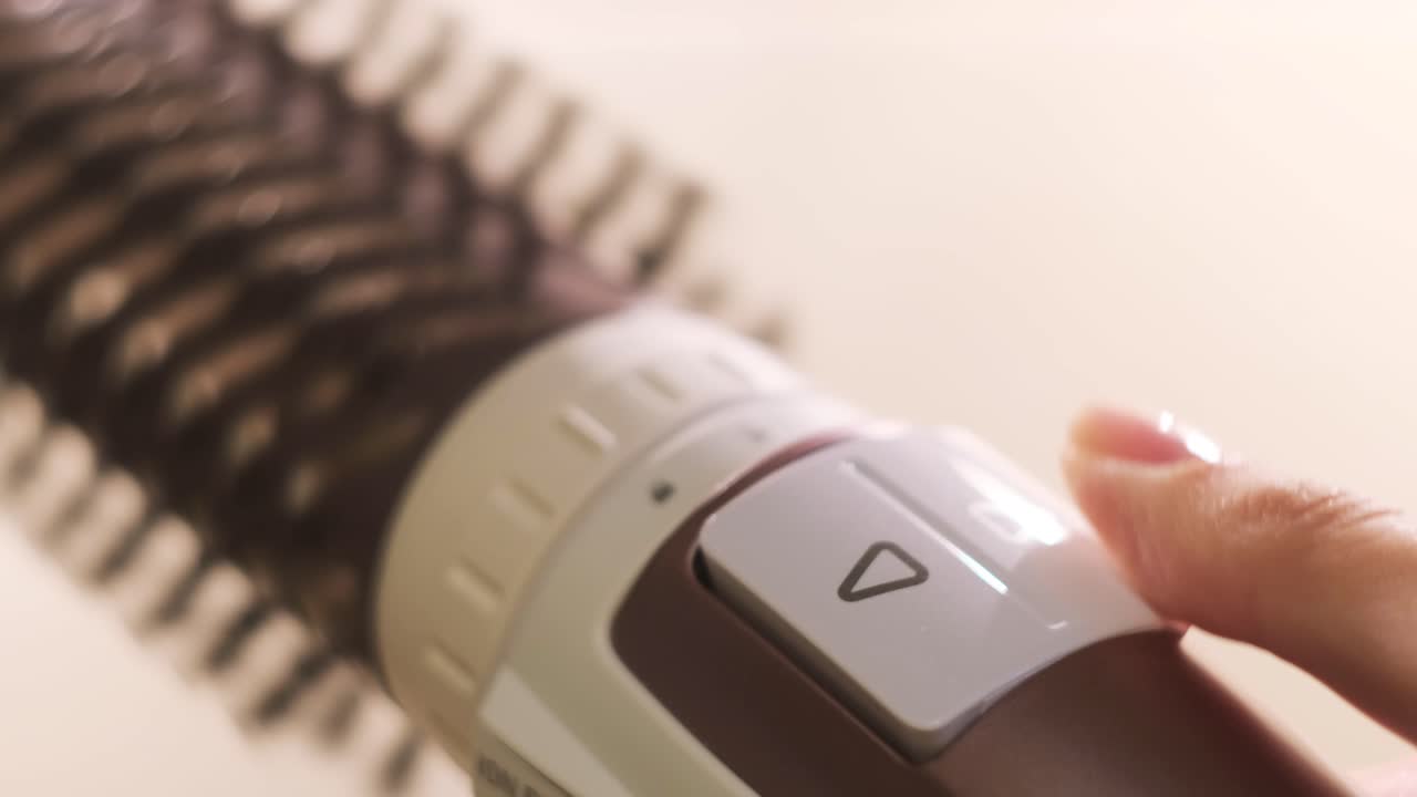 뜨거운 스타일링 브러쉬의 스위치를 만지는 여성의 손