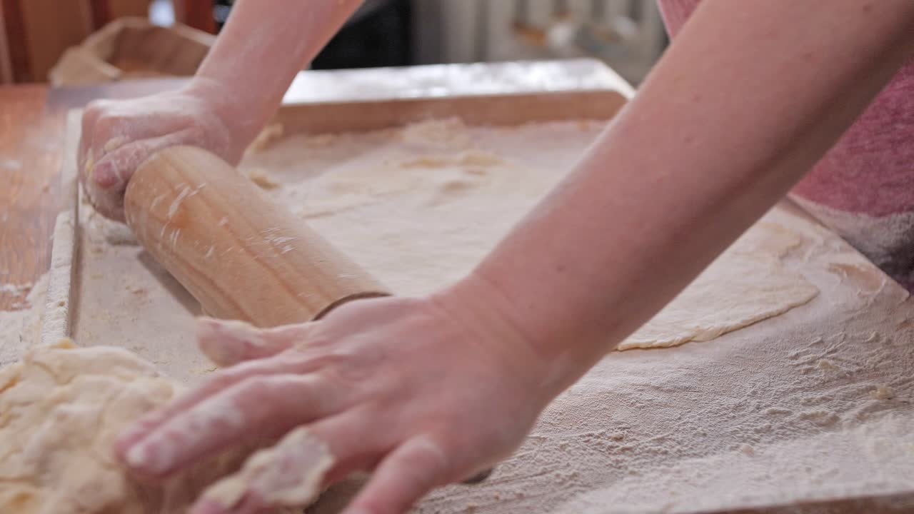 Donna, casalinga, stende l'impasto con un mattarello sulla spianatoia