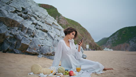 carefree woman checking mobile phone on beach. relaxed girl rest picnic at shore