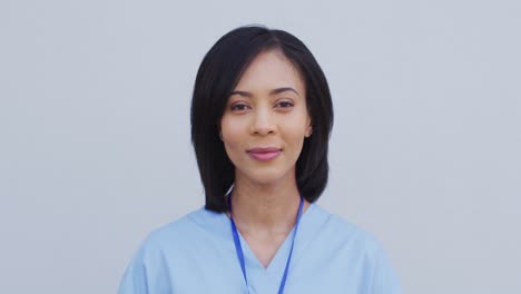 Portrait-of-female-health-worker-smiling-against-white-background