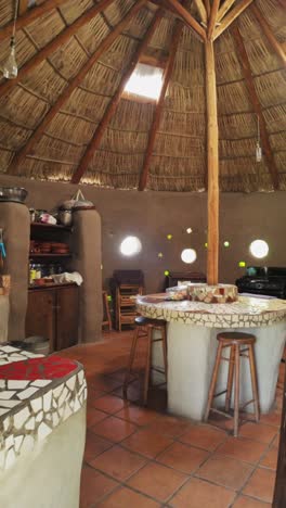 rustic kitchen with thatched ceiling, mosaic counter, and round windows, vertical shot