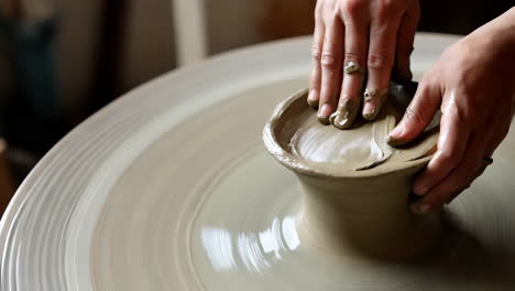 woman shaping clay on a pottery wheel