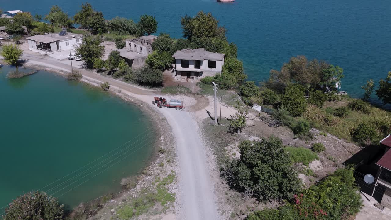 Tractor pulls water tank to wet dry sediment along Green lake, Taurus mountains Turkey