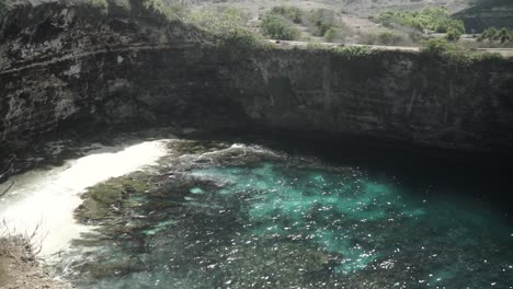 high angle view over private hidden white sand beach surrounded rocky cliffs, pan right