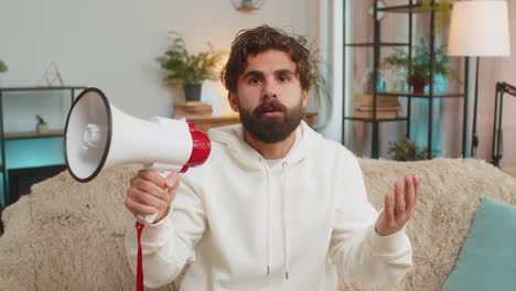 young man in hoodie shout in megaphone loudspeaker announces discounts sale at home apartment