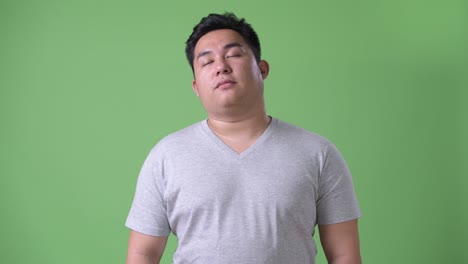 초록색 배경에 젊은 잘생긴 과체중 아시아인
