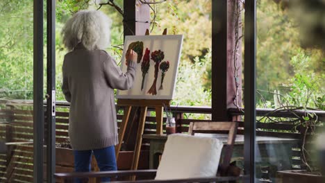 senior mixed race woman painting on balcony