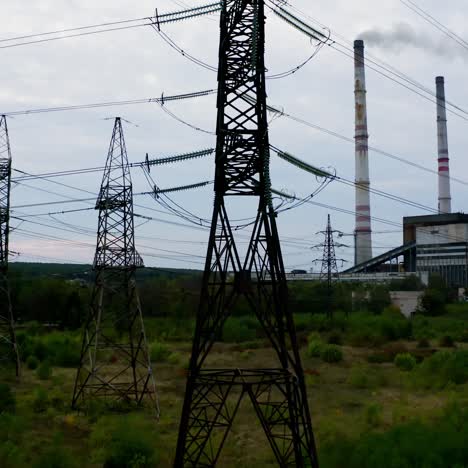high-voltage electric tower. transmission lines on the background of industrial factory. steel power pylons on field in the countryside. camera rising up.