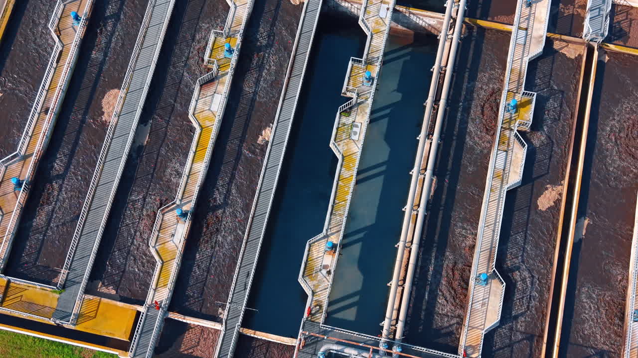Close up of metal walkways over aeration tanks. Detailed aerial view of industrial infrastructure featuring walkways and pipes over wastewater aeration basins