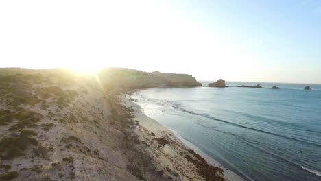 Rocky-coastline-at-sunset-in-a-slow-descending-aerial