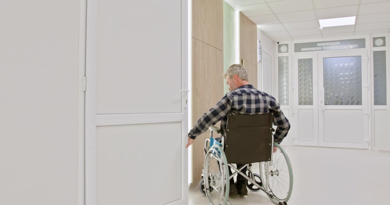 Uomo di mezza età su una sedia a rotelle in una stanza d'ospedale, concetto di recupero, disabilità e assistenza sanitaria