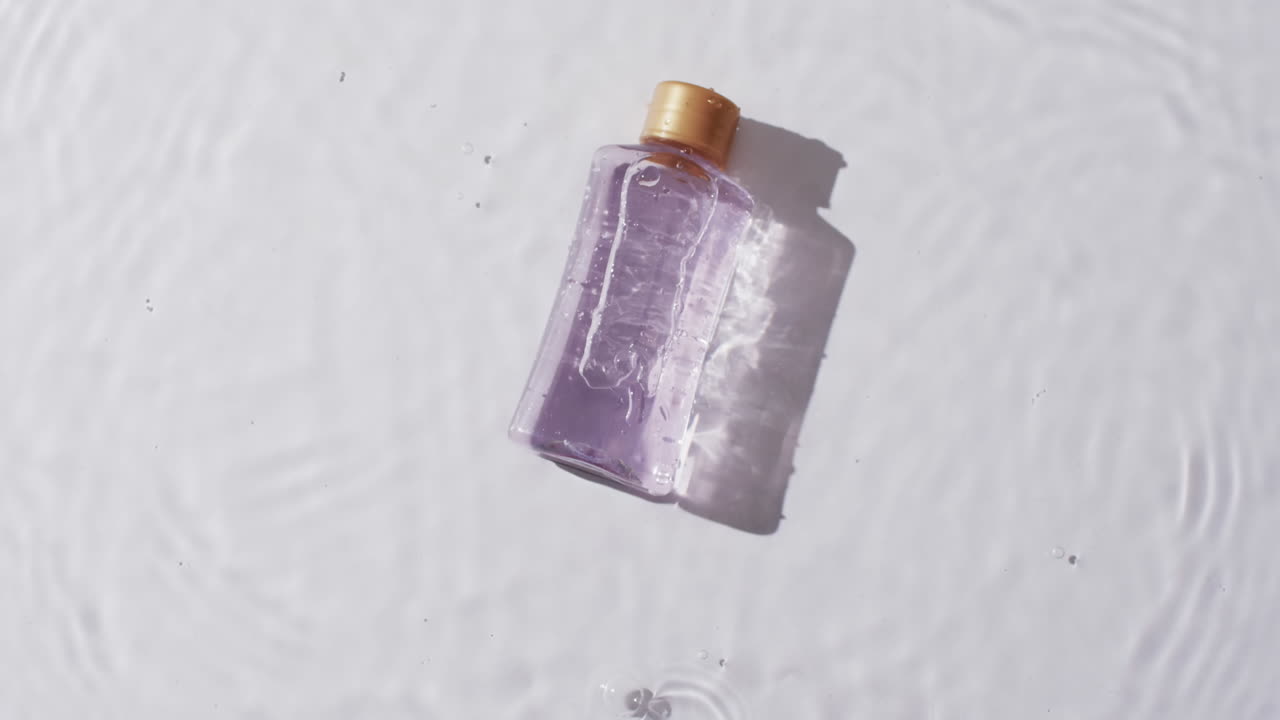 video de una botella de producto de belleza en agua con espacio de copia en fondo blanco