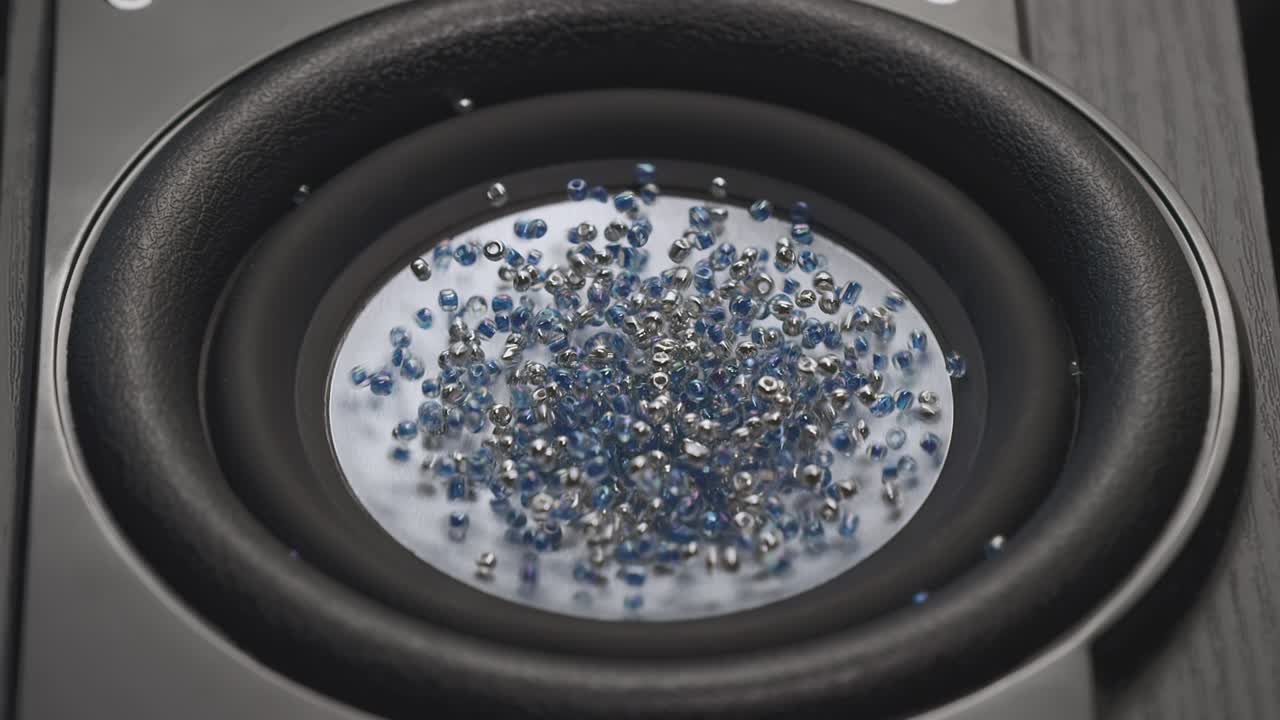 떨리는 스피커가 파란색과 금색 입자를 던집니다. 녹음 스튜디오에서 바스 사운드 파티 또는 콘서트 영상 바스 큰 스피커는 공중에 먼지를 던집니다 슈퍼 슬로 모션 이라이저 개념