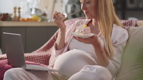 pregnant woman watching movie online and eating dessert