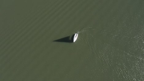 drone shot of a sailboat turning around in a lake