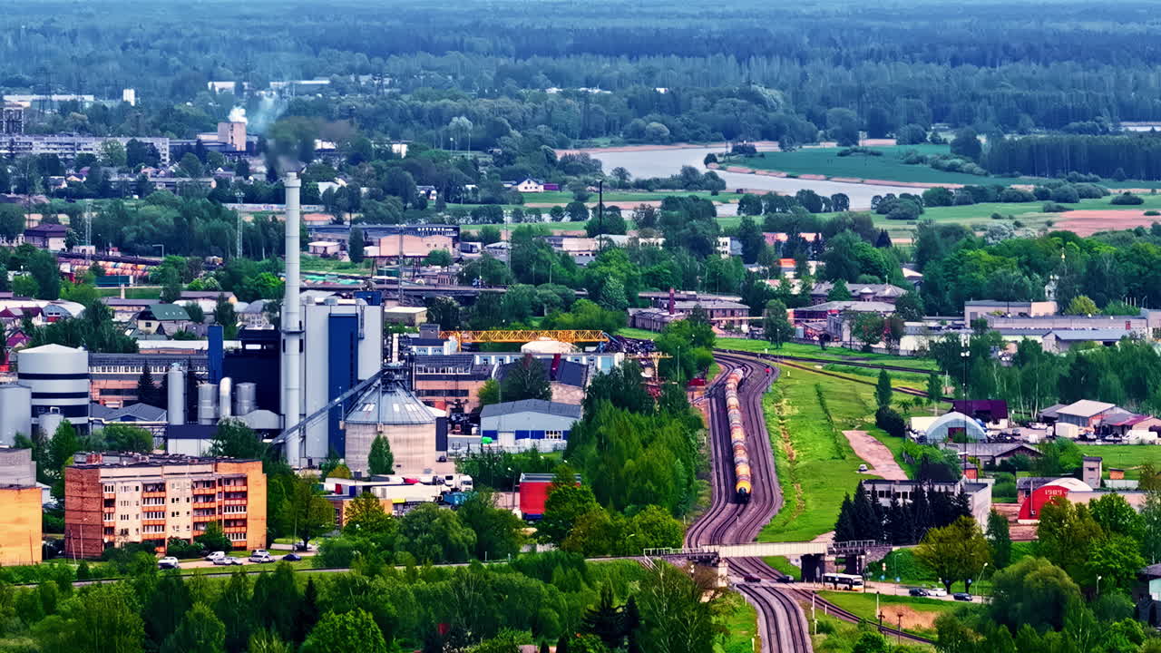 Urban industrial zone surrounded by greenery, with cars moving along busy neighborhood streets.