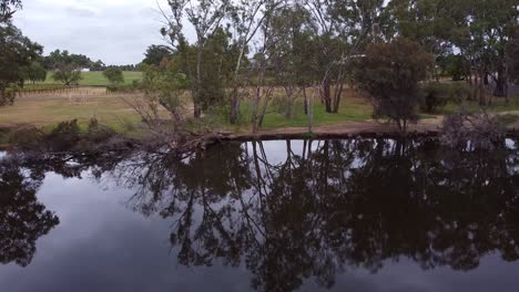 Aerial-dolly-footage-of-dark-still-water-towards-trees-on-opposite-bank