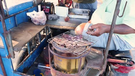 vendedor asando calamares en una estufa de carbón.