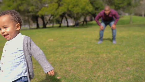 Kleiner-Junge-Gemischter-Abstammung-Im-Park,-Der-Vom-Vater-Zur-Mutter-Rennt