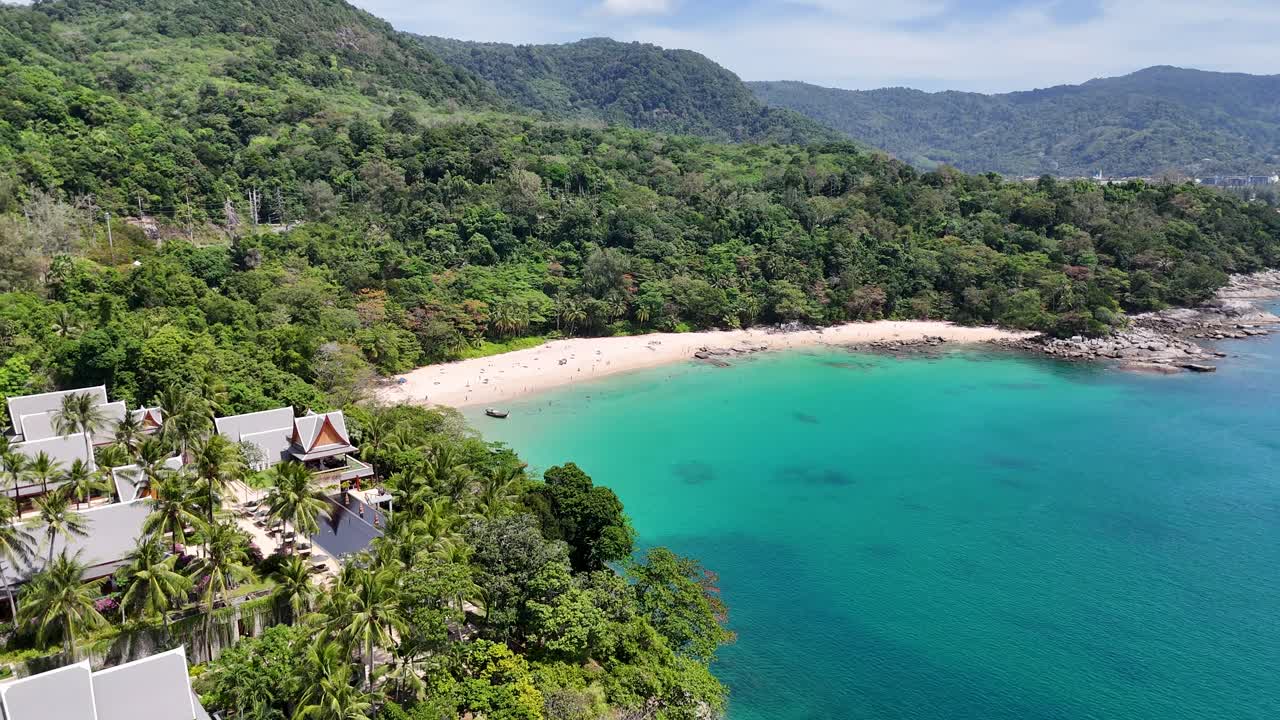 Drone footage captures lush greenery, turquoise waters, and beachfront resorts in Phuket, Thailand, showcasing serene coastal beauty