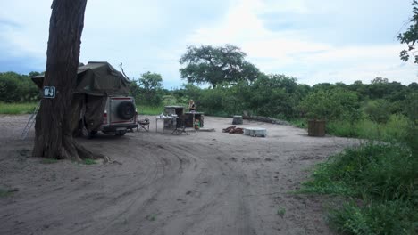 amplio lugar de campamento africano con un crucero 4x4 y una mujer joven limpiando