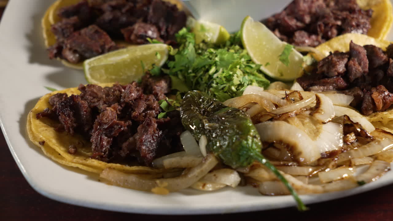 Traditional carne asada steak street tacos on corn tortillas with grilled onions cilantro and borracho beans, close up slider 4K