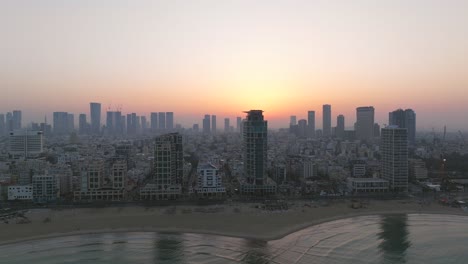 Tel-Aviv-coastline-at-sunrise-with-beautiful-calm-waters-of-The-Mediterranean-Sea,-Waterfront-hotels-and-light-sun-flare