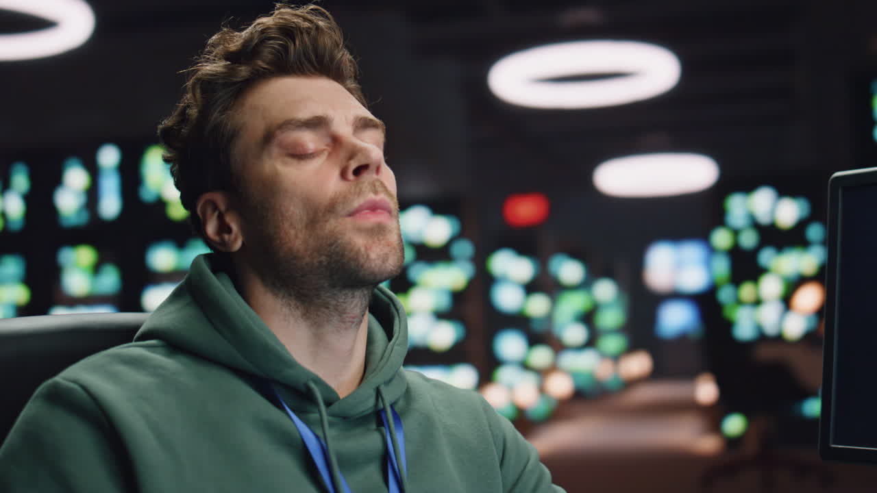 Overworked analyst drinking coffee coding at computer data center workplace