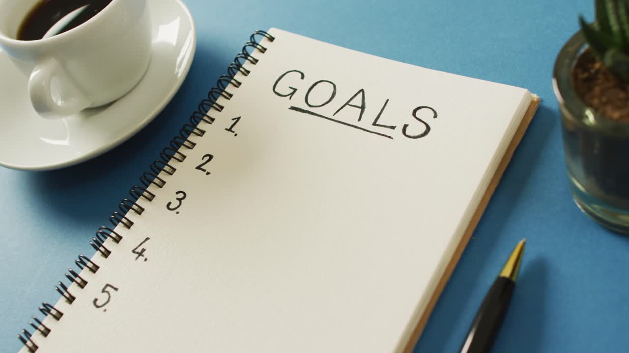 目標とコピースペース,青い表面のコーヒーと ⁇ 筆のノートブックのビデオ